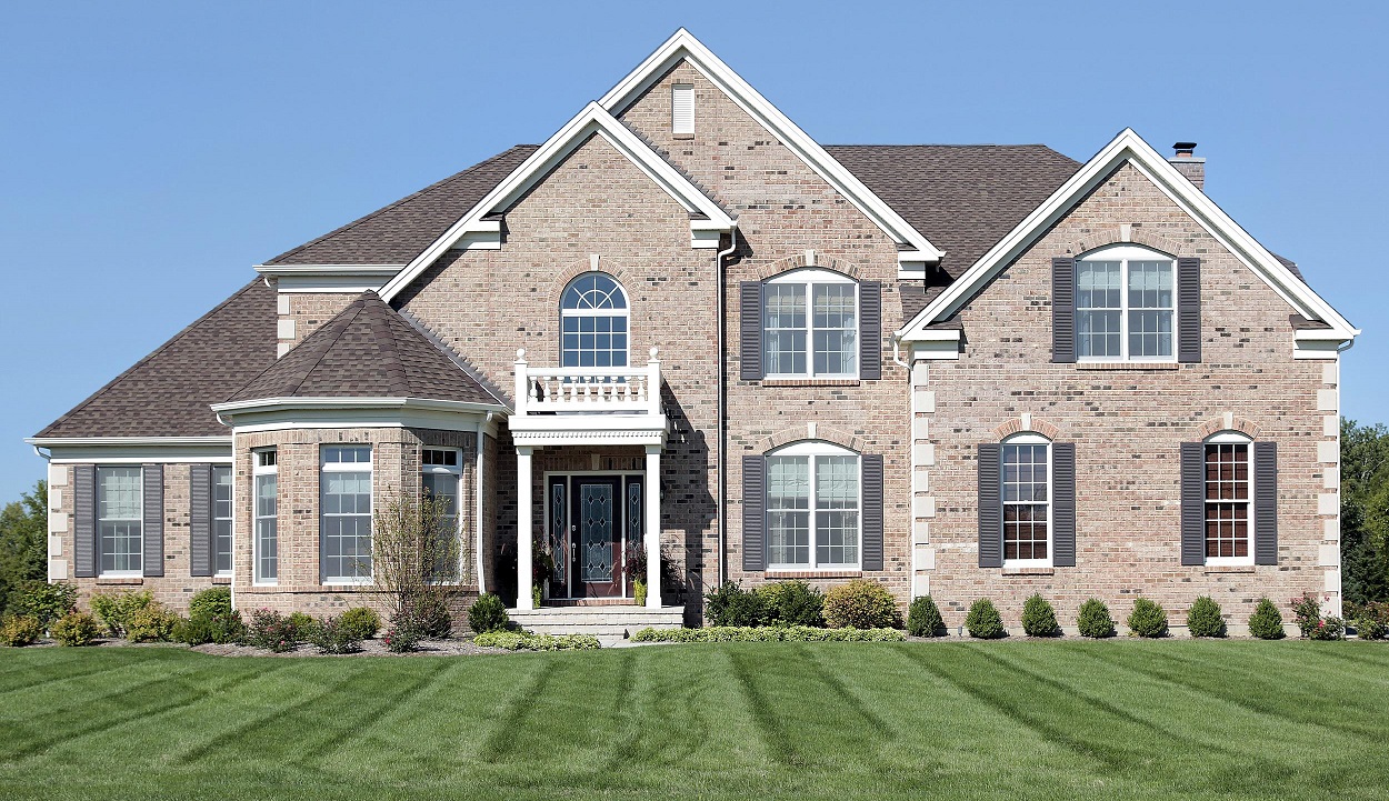 big brick house with custom landscape and green grass